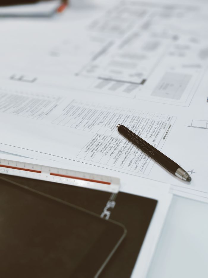 Mastering the First Impression: Your intriguing post title goes here Top view of architectural blueprints, pen, and scale ruler on a designer's desk, showcasing a creative workspace.